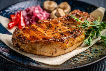 grilled pork steak with herbs and vegetables on plate
