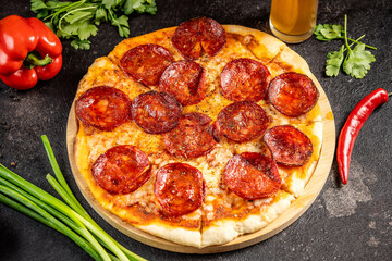hot pepperoni pizza with salami slices on wooden board