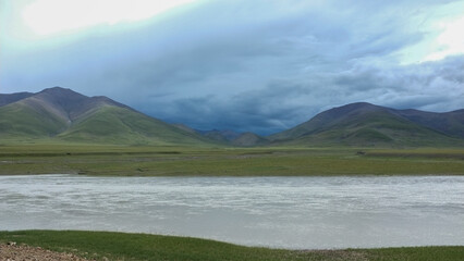 Naklejka premium Scenic landscape with river and mountains under cloudy sky