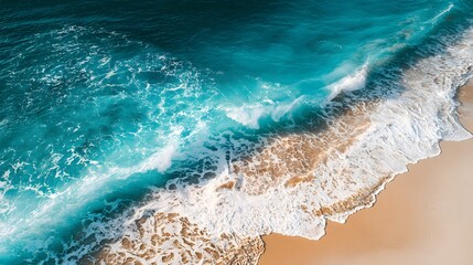 Turquoise ocean waves crash onto a sandy beach from above.