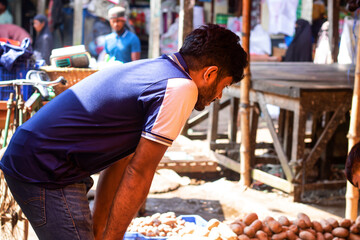 Hardworking vendor carefully sorting potatoes at vibrant outdoor market, ensuring quality produce for customers, promoting local agriculture and fresh food access, supporting community