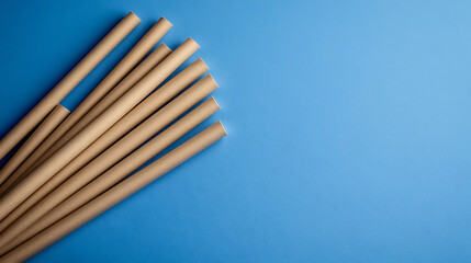 Obraz premium Beige paper drinking straws are arranged in a pile against a vibrant blue background. The composition suggests an eco-friendly lifestyle.