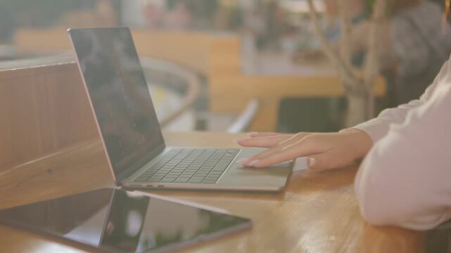 Person is typing on a laptop computer. There is a tablet on the table next to the laptop