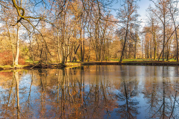 Obraz premium Autumn Reflections: Still lake mirrors the surrounding trees in their fall colors, creating a serene and beautiful landscape.