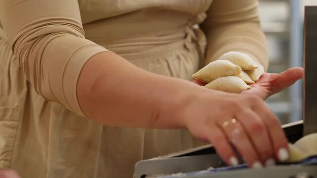A person holds a handful of fresh perogies in a cozy kitchen. The atmosphere is warm, showing the joy of cooking homemade meals during a sunny afternoon.