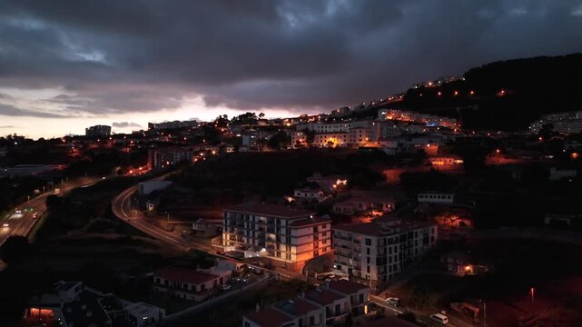 Evening drone cityscape view with illuminated houses and apartments on hillside, Portugal