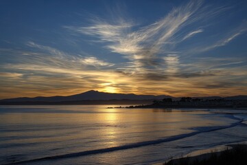 Fototapeta premium Sunset over calm ocean, mountain backdrop
