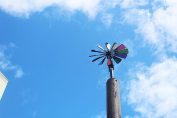 Windmill wind direction indicator against blue sky background