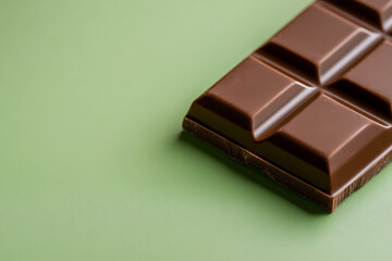 Delicious dark chocolate bar on a solid color background. Close-up view of tasty confectionery with square indentations, smooth, and shiny surface.