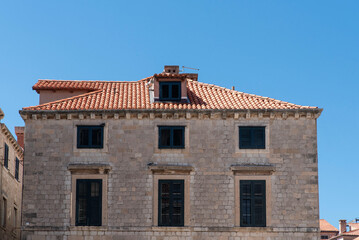 Limestone building with terracotta roof and green shutters
