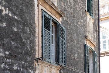 Weathered facade with open louver shutters
