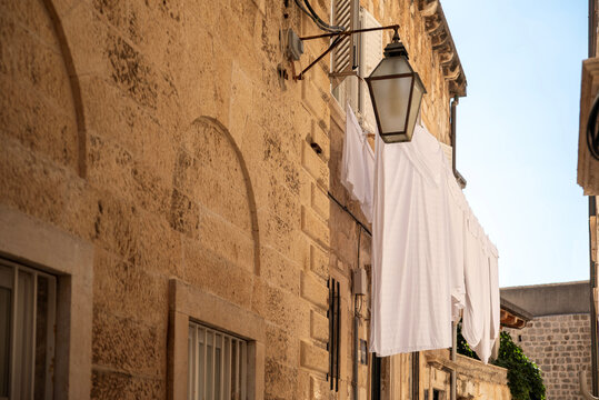 White laundry drying on stone alley facade