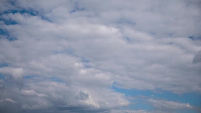Time-lapse of a soft, overcast sky with sheet-like stratus clouds drifting across frame, revealing small patches of blue as the gray cloud cover moves steadily, creating a calm, muted background.