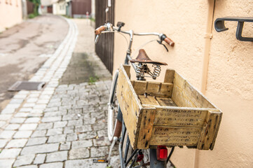 Historisches Fahrrad mit verwitterter Holzkiste auf Gepackträger in Gasse an der Bergermauer mit Kopfsteinpflaster in der Altstadt von Nördlingen am Berger Tor