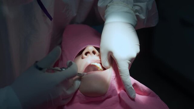 A dental team is injecting local anesthesia with a sterile syringe before performing an impacted wisdom tooth extraction surgery in the mouth.