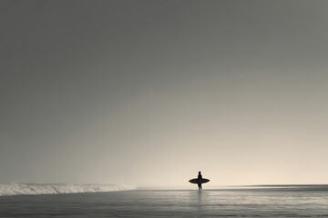 A solitary surfer with a surfboard stands in the calm ocean at dawn.