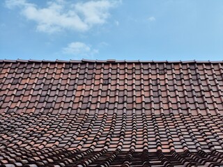 photo of an arrangement of clay roof tiles on a pavilion with a blue sky and white clouds in the background