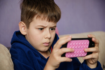 Young boy engrossed in watching a video or playing a game on a smartphone.