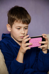 Young boy engrossed in watching a video or playing a game on a smartphone.