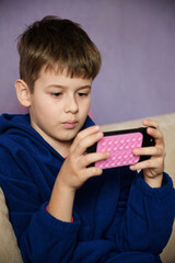 Young boy engrossed in watching a video or playing a game on a smartphone.