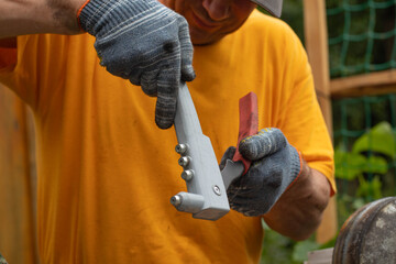Riveter. A gloved hand holding a riveter. A manual riveting tool.
