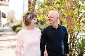 Obraz premium Senior happy couple of stylish man and woman 60-65 year old walking together on streets holding hands at city outdoors. Wellness lifestyle. Happiness.
