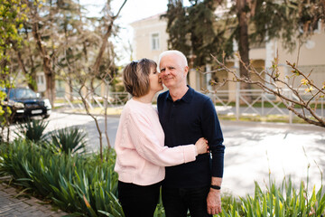 Senior happy couple of stylish man and woman 60-65 year old walking together on streets holding hands at city outdoors. Wellness lifestyle. Happiness. Looking at each other