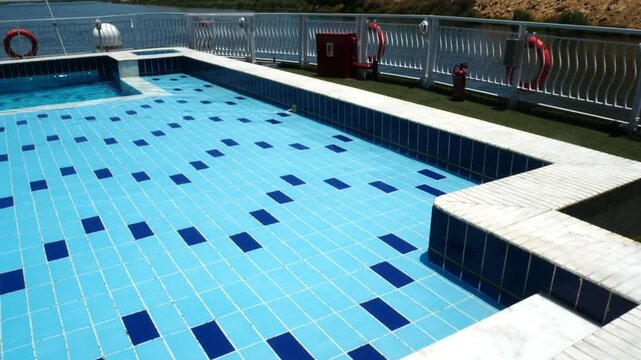 Swimming pool with blue calm waters, on a cruise ship on the river Nile, Egypt. Natural landscape on the background, with sahara desert hills and blue sky.