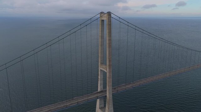 Drone shot of Great Belt Bridge with heavy vehicles crossing sea.