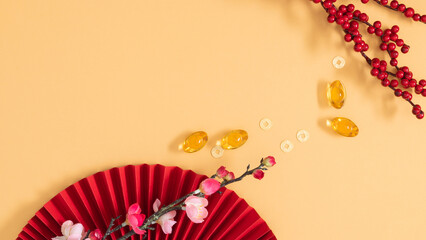 Minimal composition with cherry blossom branch, red fan, and golden coins on peach background....