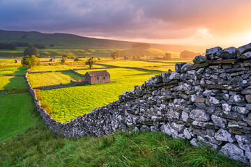 Dry stone wall with traditional barn in rural fields of The Yorkshire Dales National Park.