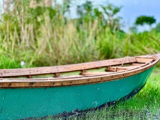 Tranquil turquoise rowboat resting peacefully on grassy riverbank, inviting serene adventures and peaceful escapes into nature's embrace