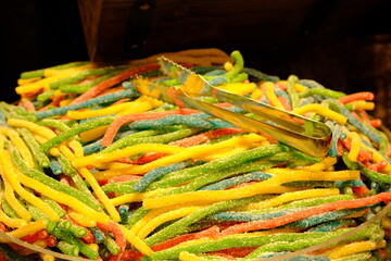Colorful worm gummy bears sold in a candy store, close-up. Long worm-shaped gummy bears for...