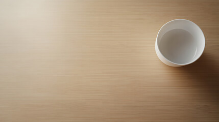 Simple serenity: White bowl partially filled with water placed on a wooden surface, offering a calming, minimalist aesthetic.