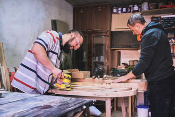 Two men working with wood in a workshop in a garage. Craftsman working on wood in a workshop