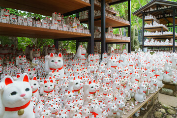 Tokyo, Japan - Sep 30 2024, A close-up view of many multi-sized white beckoning cat figure of Maneki neko with red ears and noses displayed at Gotokuji Temple, without people, at daytime, Tokyo, Japan
