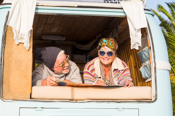Senior couple standing next to a vintage camper van during a road trip, smiling and in love, concept of active lifestyle, freedom, travel, romance, adventure, eternal love, age is just a number
