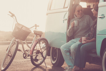 Senior couple standing next to a vintage camper van during a road trip, smiling and in love, concept of active lifestyle, freedom, travel, romance, adventure, eternal love, age is just a number
