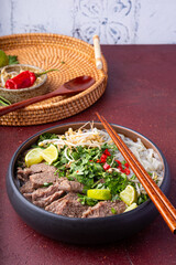 Pho Bo Vietnamese soup, bowl of fresh asian soup with rice noodle, beef meat, herbs, soy sprouts and chili on table. Asian cuisine, comfort food.