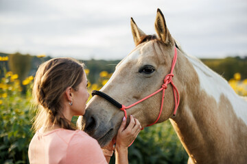 Affectionate moment between woman and her horse. Female rancher standing close to her paint horse expressing trust and friendship