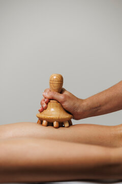 Close-up of wood therapy massage tool used on leg in wellness session.