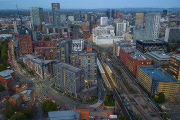 Aerial view above Salford Central Station at dusk, facing Manchester city centre with rail lines and city lights