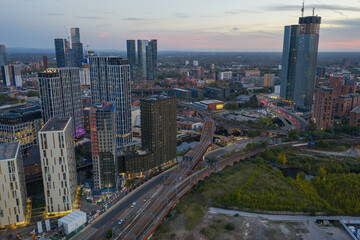 Aerial evening view of Manchester's Deansgate Square and Trinity Islands skyline with Trinity Way, River Irwell, and Ordsall Bridges.