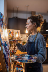 Artist creates a vibrant painting in a cozy studio filled with warm light during evening hours