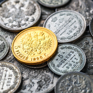 Gold and silver coins of the Russian Empire19-20 century.Five rubles Nicholas II.Concept Russian antiques.Numismatics.Collection of old coins.A collector holds an old coin.Magnifying glass.
