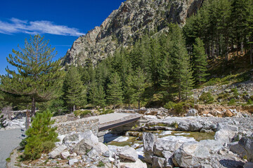 a destroyed bridge in the hiking area of the Restonica Valley with lots of debris in the sunshine