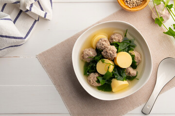 Vegetable gourd soup with minced pork and tofu in white bowl on wooden table,Thai food.(gaeng jued tum luang).Top view