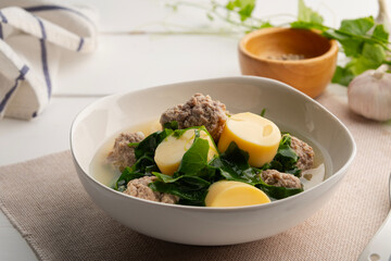 Vegetable gourd soup with minced pork and tofu in white bowl on wooden table,Thai food.(gaeng jued tum luang)