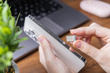 Person's hand holds a sleek smartphone, preparing to insert a nano SIM card, representing essential mobile network setup and modern telecommunications technology