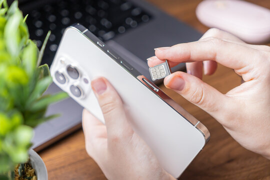 Human hand carefully installing a new nano SIM card into a sleek white smartphone, symbolizing essential mobile communication setup, activation, and network service